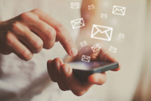 pessoa clicando no celular. ícones que simbolizam emails representam a abertura de uma newsletter